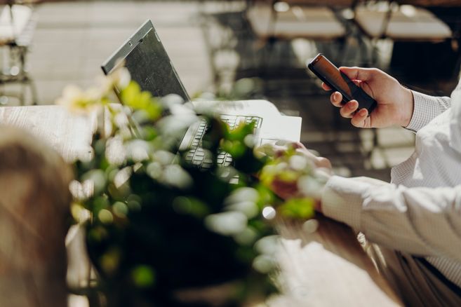 Mann sitzt draußen an einem Laptop und Arbeitet