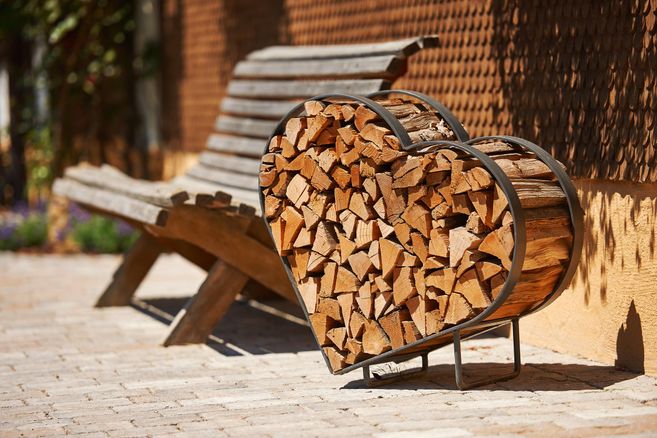 A heart-shaped stack of wood stands next to a wooden bench. The scene has a warm, inviting atmosphere.